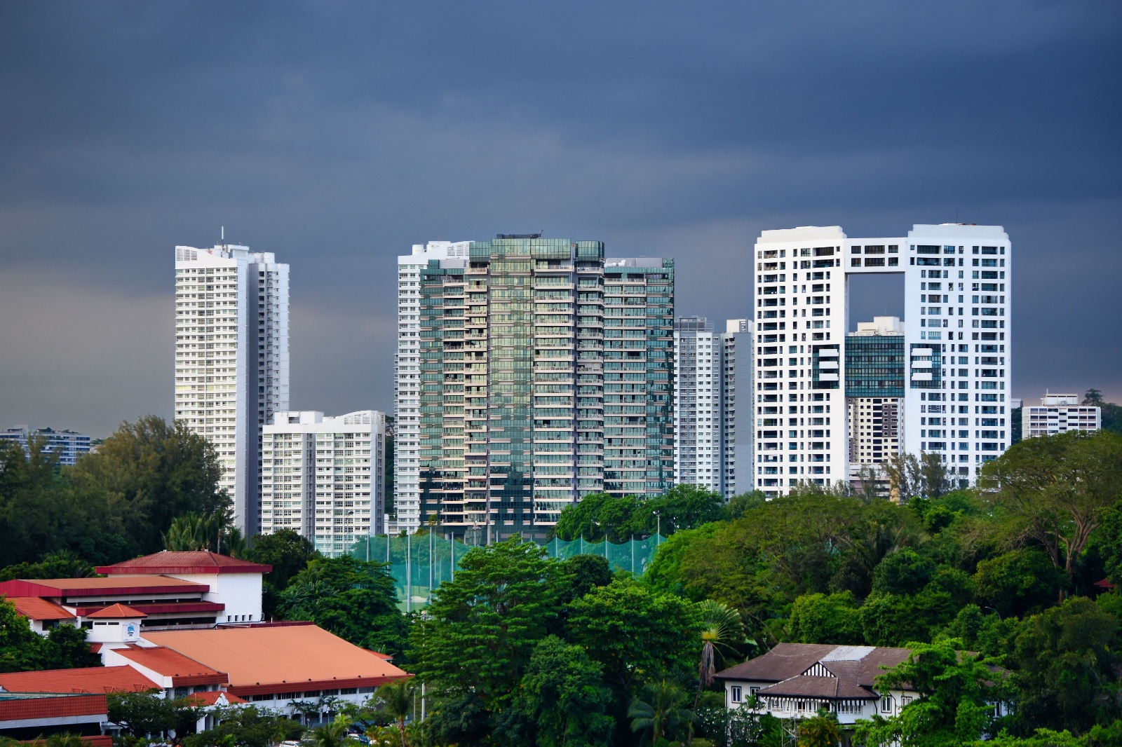 High-rise buildings above a green Singapore neighbourhood under a cloudy sky